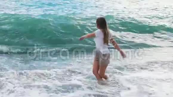 美丽的年轻姑娘玩着大海的浪花视频的预览图