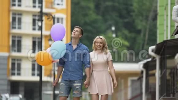 女朋友和男朋友带着气球走在街上停下来亲吻视频的预览图