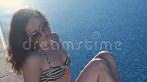 坐在游泳池旁的寂寞女人阳光明媚的夏日海滩视频的预览图