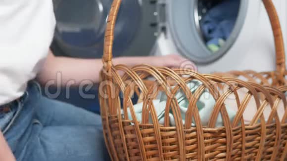 特写镜头女人从烘干机里拿出衣服放在柳条筐里视频的预览图