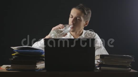穿着疲惫的商人在工作场所喝伏特加经理喝酒晚上在办公室工作视频的预览图