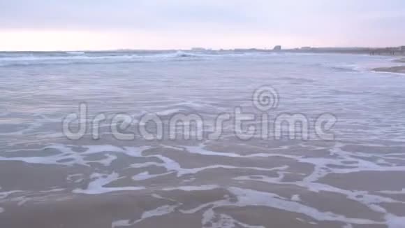 大海里波涛汹涌美丽的海景与沙滩和海岸小镇背景在日落视频的预览图