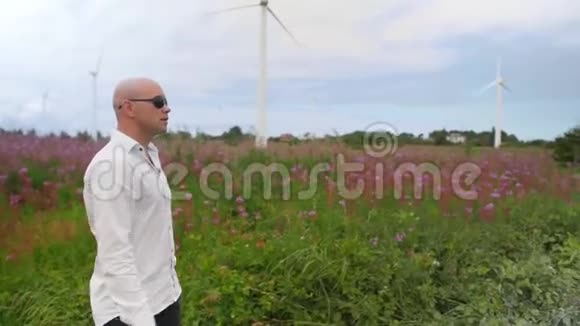人类走过田野在风力涡轮机能源生产的背景下歌唱中弹视频的预览图