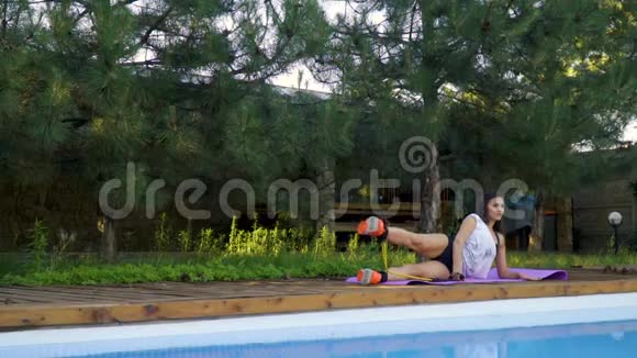 这位女运动员躺在游泳池旁腿上放着针叶树动作缓慢视频的预览图