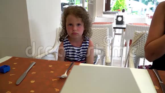 漂亮的小女孩坐在厨房的桌子旁用双手表示喜悦视频的预览图