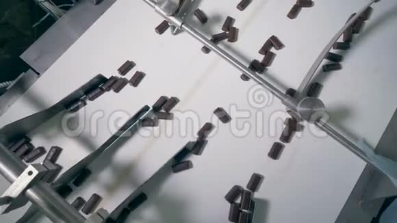一排排巧克力糖果沿着传送带移动由一名工厂工人分类视频的预览图