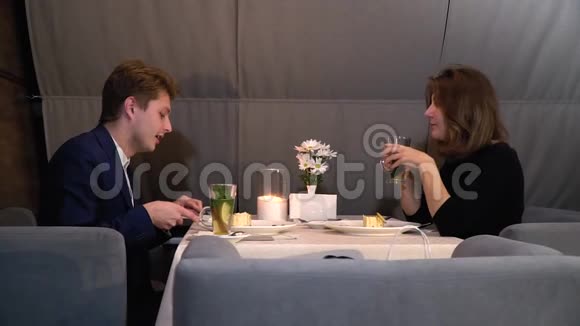 一对恩爱的情侣在一次有甜点和茶的约会中坐在餐厅的沙发上滑滑梯拍摄有点慢视频的预览图