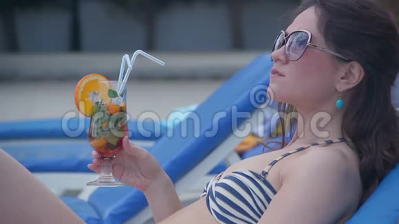 辣妹在海滩上喝新鲜鸡尾酒用舌头逗弄视频的预览图