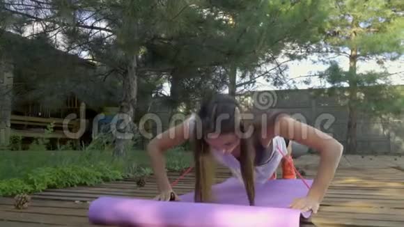 苗条的女孩俯卧撑在地毯上做瑜伽背景中有一个大球做瑜伽慢镜头拍摄视频的预览图