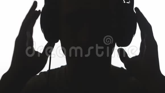 合上人的剪影戴上耳机在白色背景上孤立地听音乐视频的预览图