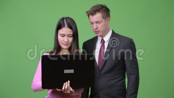 年轻的亚洲妇女和年轻的商人一起使用笔记本电脑视频的预览图
