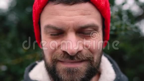 一个戴红帽子的男人在户外下雪时的肖像视频的预览图