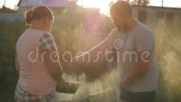 快乐夫妇在烧烤架上煮香肠一对夫妇在野餐时边吃边喝快乐的人视频的预览图