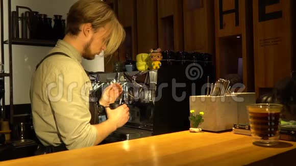 一位留着胡子的咖啡师金发碧眼在咖啡机上蒸牛奶一间舒适的咖啡屋视频的预览图