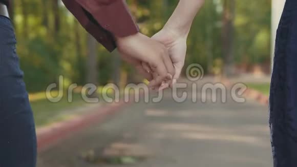 年轻夫妇从近距离的后视角握着手走在一起视频的预览图
