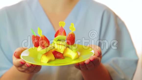 那个女人厨师微笑着拿着一个盘子手里拿着一份水果甜点控制来自窗户的阳光视频的预览图