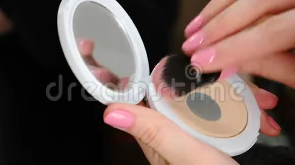 特写女人她的手与化妆粉和镜子做化妆使用刷子视频的预览图