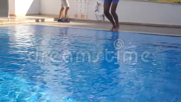 阳光明媚的日子肌肉发达的男人在盆里跳着年轻人在游泳池游泳慢动作关闭视频的预览图