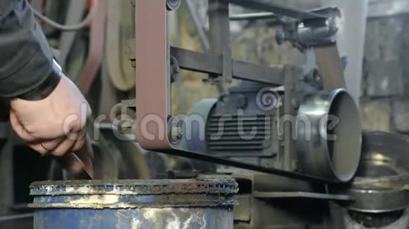 在皮带研磨机上研磨金属刀的坯料男人的手特写视频的预览图
