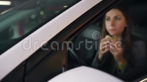 在停车场坐在车里吃三明治的女人现代忙碌生活的概念视频的预览图