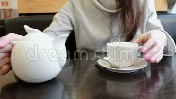 女人的手特写把茶壶里的茶倒进杯子里侧视视频的预览图