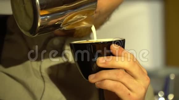 一个穿围裙的长胡子咖啡师把牛奶倒入卡布奇诺慢动作视频的预览图