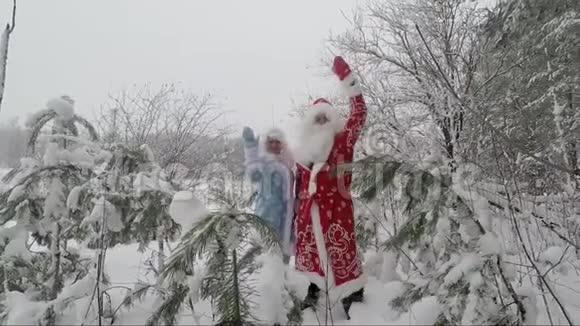 圣诞老人和孙女高兴地在白雪覆盖的森林里挥手慢动作视频的预览图