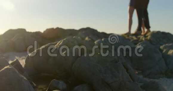 浪漫的年轻夫妇在海滩上拥抱岩石视频的预览图