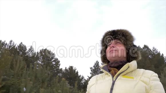 严冬森林里呼吸新鲜空气的老妇人视频的预览图