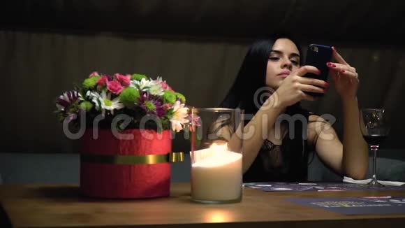一个女人坐在一家餐馆里端着一杯酒用智能手机打印短信有点慢动作视频的预览图
