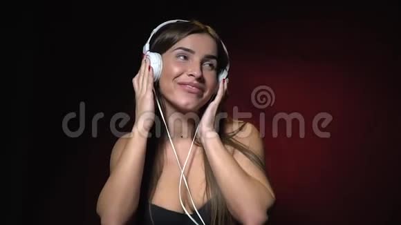 一个穿着黑色胸罩的黑发女人站着用耳机听音乐视频的预览图