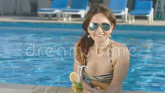 美丽的女孩比基尼在游泳池放松享受鸡尾酒度假视频的预览图
