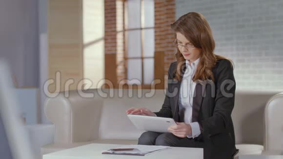 从事平板电脑工作的女性金融分析师微笑着寻找相机视频的预览图