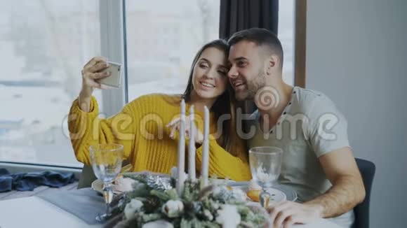 快乐的微笑情侣在室内咖啡厅用智能手机吃午餐和自拍视频的预览图