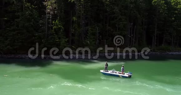 阳光明媚的一天两个人在河里钓鱼在船上航行视频的预览图