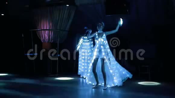 穿着白色发光二极管服装的女孩热情地与LED风扇跳舞视频的预览图