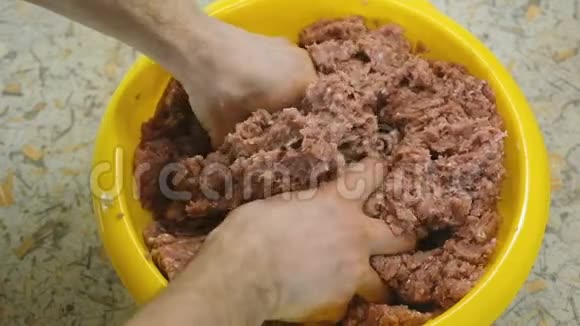 特写男人手把肉夹在黄色的盆里新鲜的肉馅慢动作视频的预览图