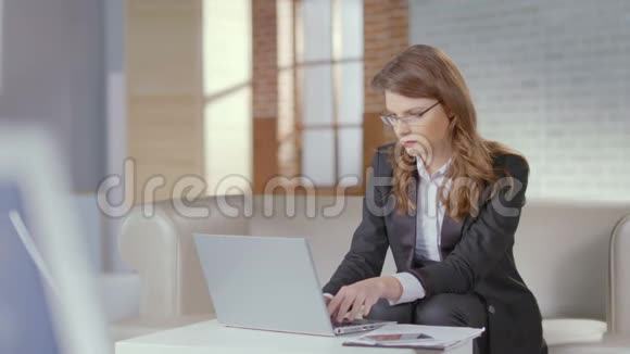 女士穿着西装戴着眼镜手提电脑对着镜头微笑视频的预览图