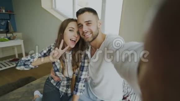 年轻的微笑和美丽的夫妇在智能手机相机上自拍坐在床上亲吻视频的预览图