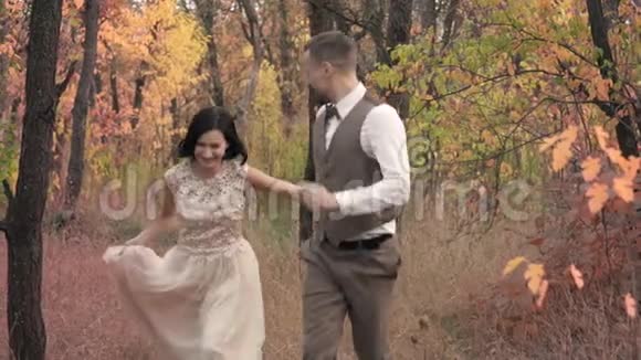 快乐的一对情侣跑在秋天的公园里微笑着慢动作视频的预览图