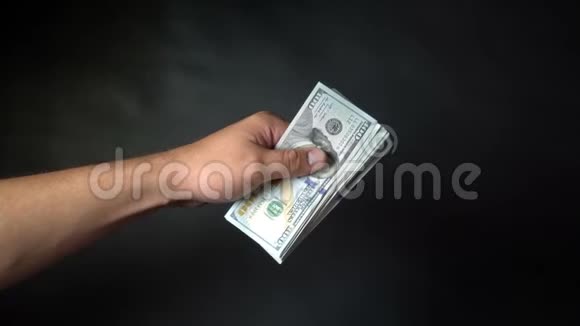 人手里的一捆钱在黑色背景上以美元取胜视频的预览图