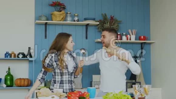 年轻快乐的一对夫妇在家厨房做饭的时候一边跳舞一边唱歌玩得很开心视频的预览图