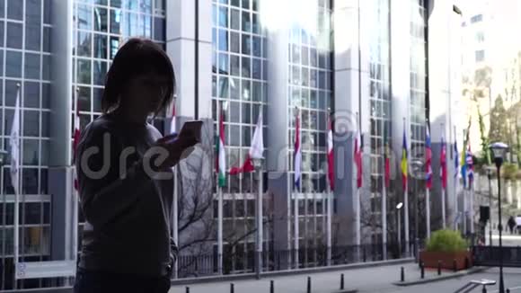 这位女士正在布鲁塞尔欧洲议会附近散步和打电话比利时慢动作视频的预览图