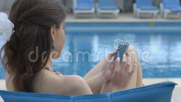 年轻女子拨打电话打电话在游泳池附近打电话视频的预览图
