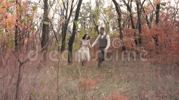 一对相爱的夫妇牵着手在秋天的公园里跑来跑去慢镜头拍摄视频的预览图