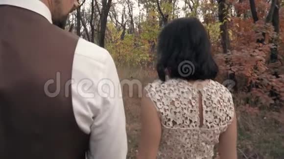一个穿着蕾丝礼服的黑发女人带着一个男人走过公园微笑着慢慢地回头看着他视频的预览图