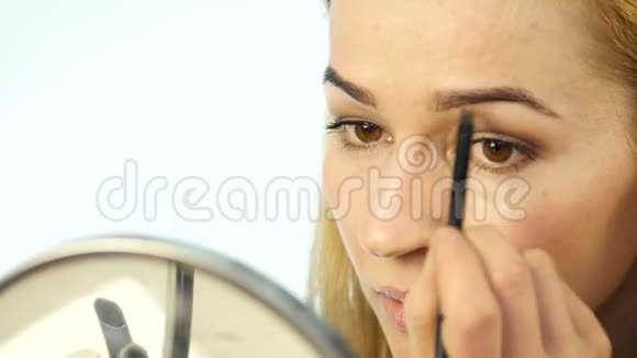 美丽的女人在小镜子前画眉毛用化妆刷做日常化妆4K视频的预览图