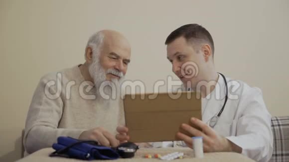 医生和老人用数字平板电脑坐在桌子旁视频的预览图