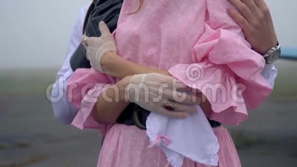 一名留胡子的男飞行员用螺旋桨轻轻地抱着一个穿着粉红色裙子的女人动作缓慢视频的预览图