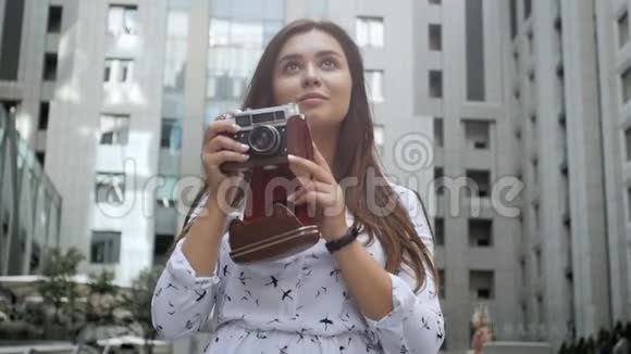 幸福微笑的黑发女孩的肖像留着长发拍摄现代建筑的照片视频的预览图